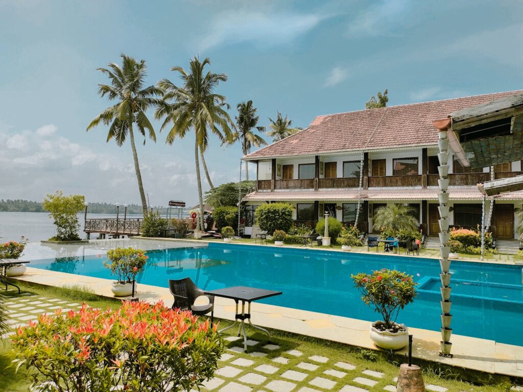 Elegant resort in Kochi, India featuring a pool surrounded by lush coconut trees, perfect for a tropical getaway.